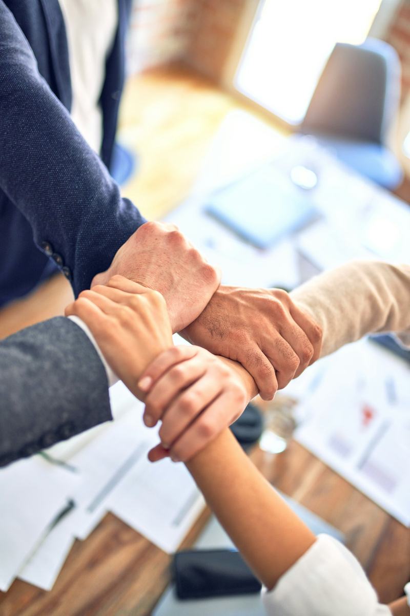 Dos personas dándose la mano al final de una reunión, con documentos sobre la mesa.