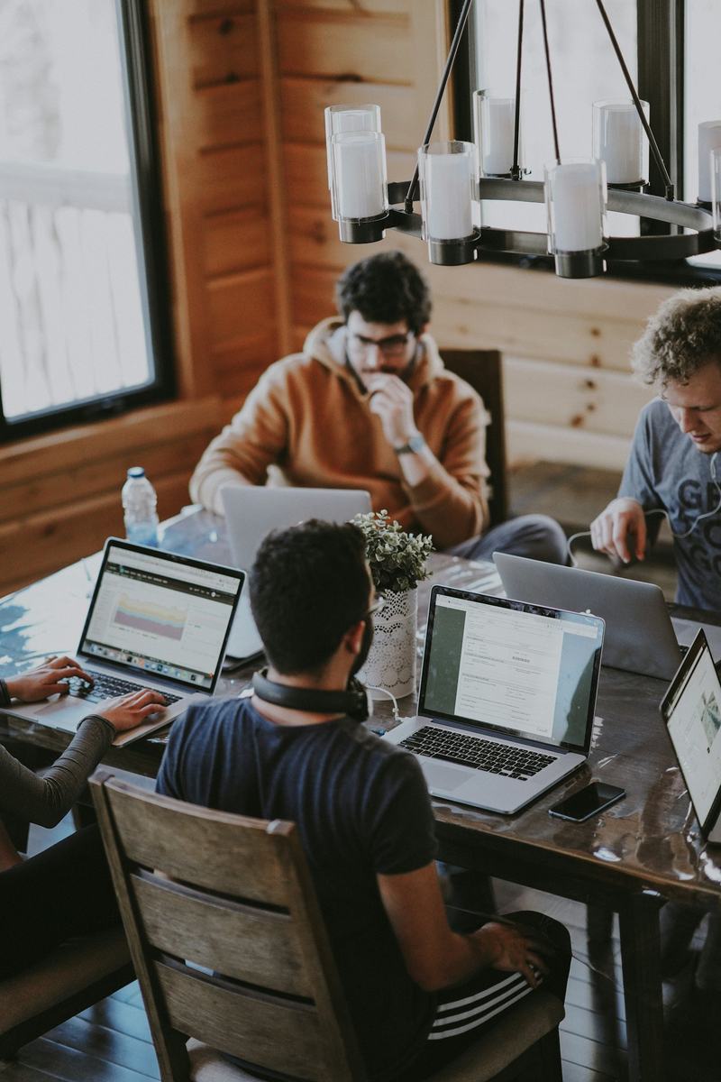 Un equipo reunido alrededor de una mesa de juntas, trabajando en un plan con sus computadoras.